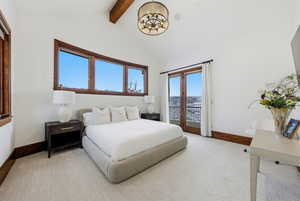 Bedroom with beamed ceiling, access to exterior, and high vaulted ceiling