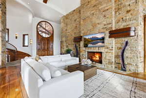 Living room with a high ceiling, hardwood / wood-style floors, a fireplace, and recessed lighting