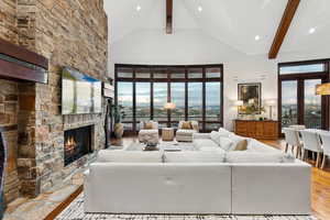 Living room featuring high vaulted ceiling, hardwood / wood-style floors, a fireplace, beam ceiling, and recessed lighting