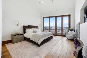 Bedroom with hardwood / wood-style flooring, access to outside, and high vaulted ceiling
