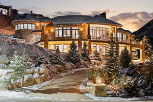 Snow covered rear of property featuring a balcony and a chimney