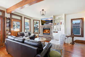 Living area with hardwood / wood-style floors, a fireplace, a textured ceiling, and beam ceiling