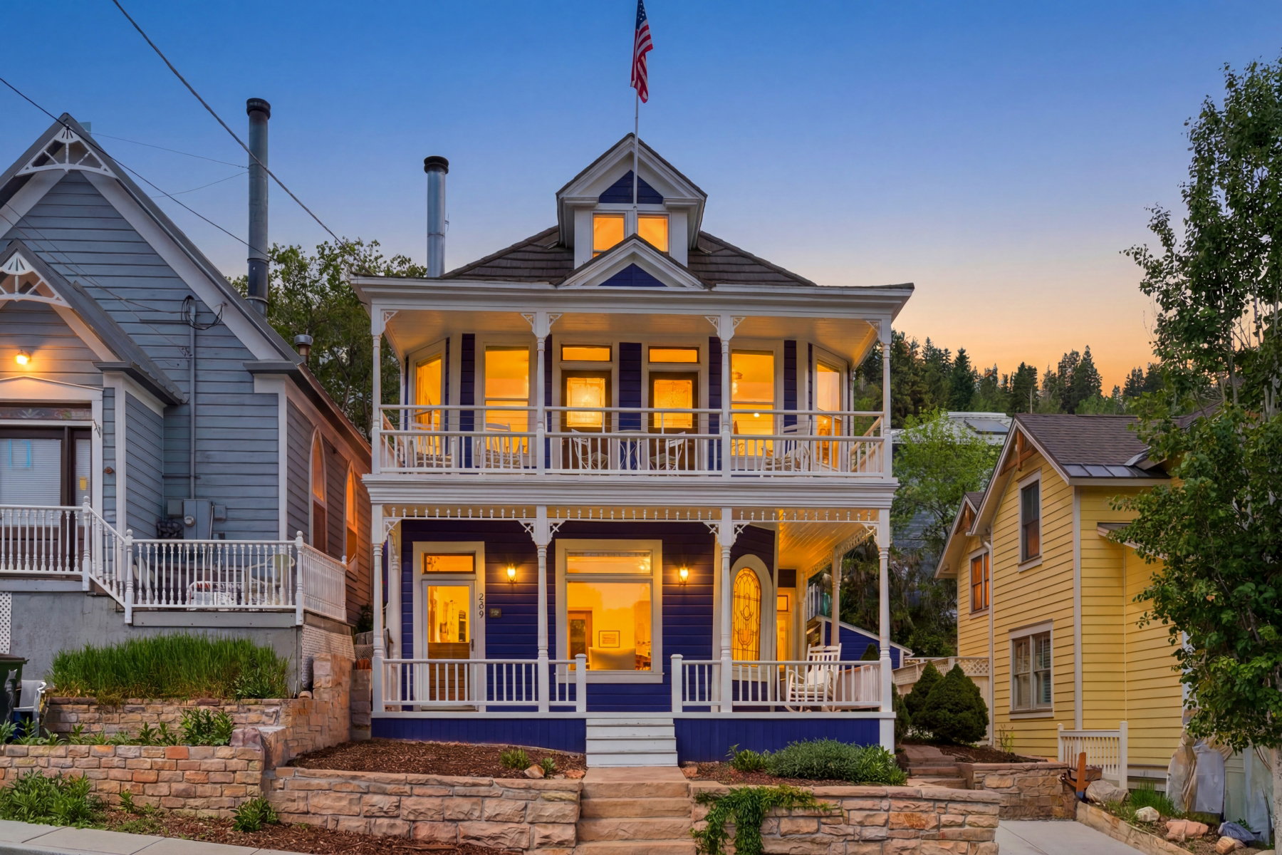 Victorian-style residence featuring a prominent two-story bay window, dual-level covered porches with ornate balustrades, and a deep blue exterior with white trim