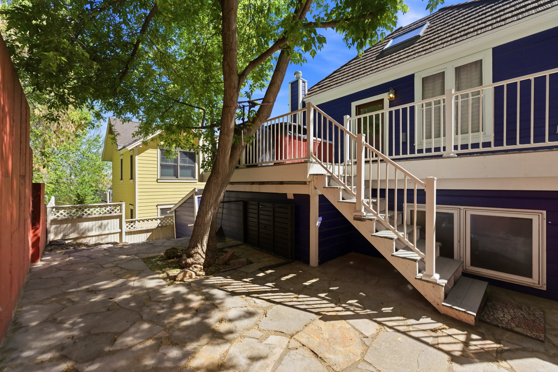 Stone patio featuring a multi-level deck with white railings and exterior stairs