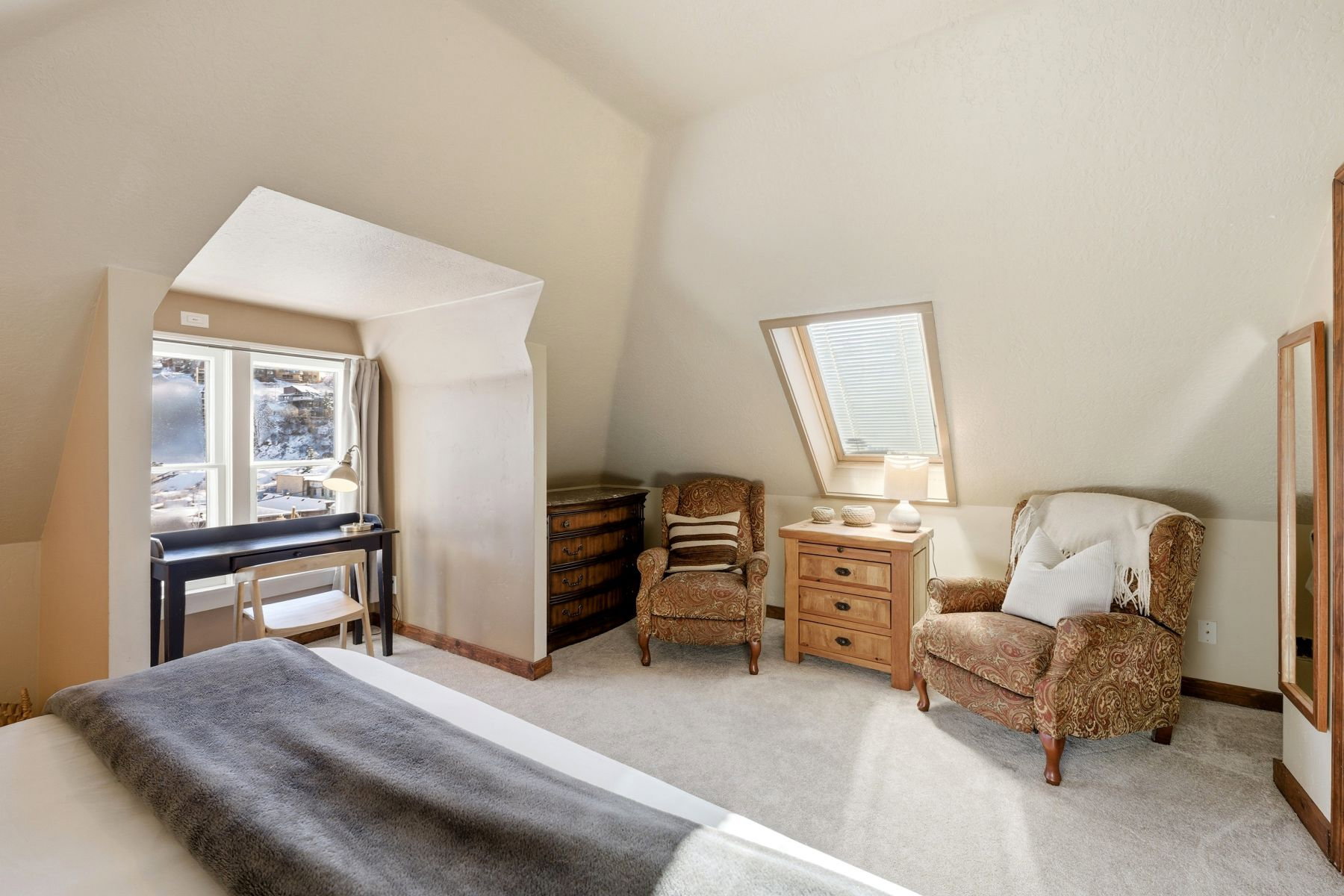 Angled ceilings featuring a skylight and a window