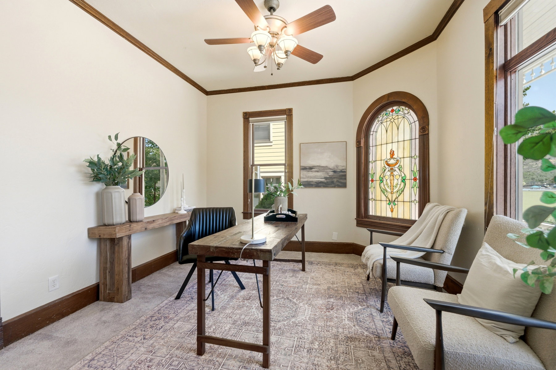Room featuring an arched stained-glass window, wood-finish trim, and a ceiling fan with light fixture