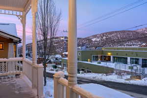 Snow covered deck featuring a mountain view and a porch
