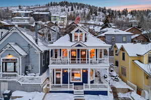 Snow covered rear of property featuring covered porch