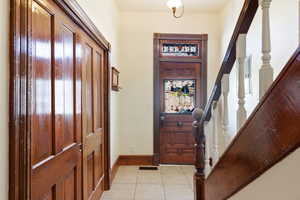 Entrance foyer with stairs and light tile patterned flooring