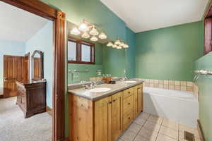 Bathroom with double vanity, a bath, and light tile patterned floors