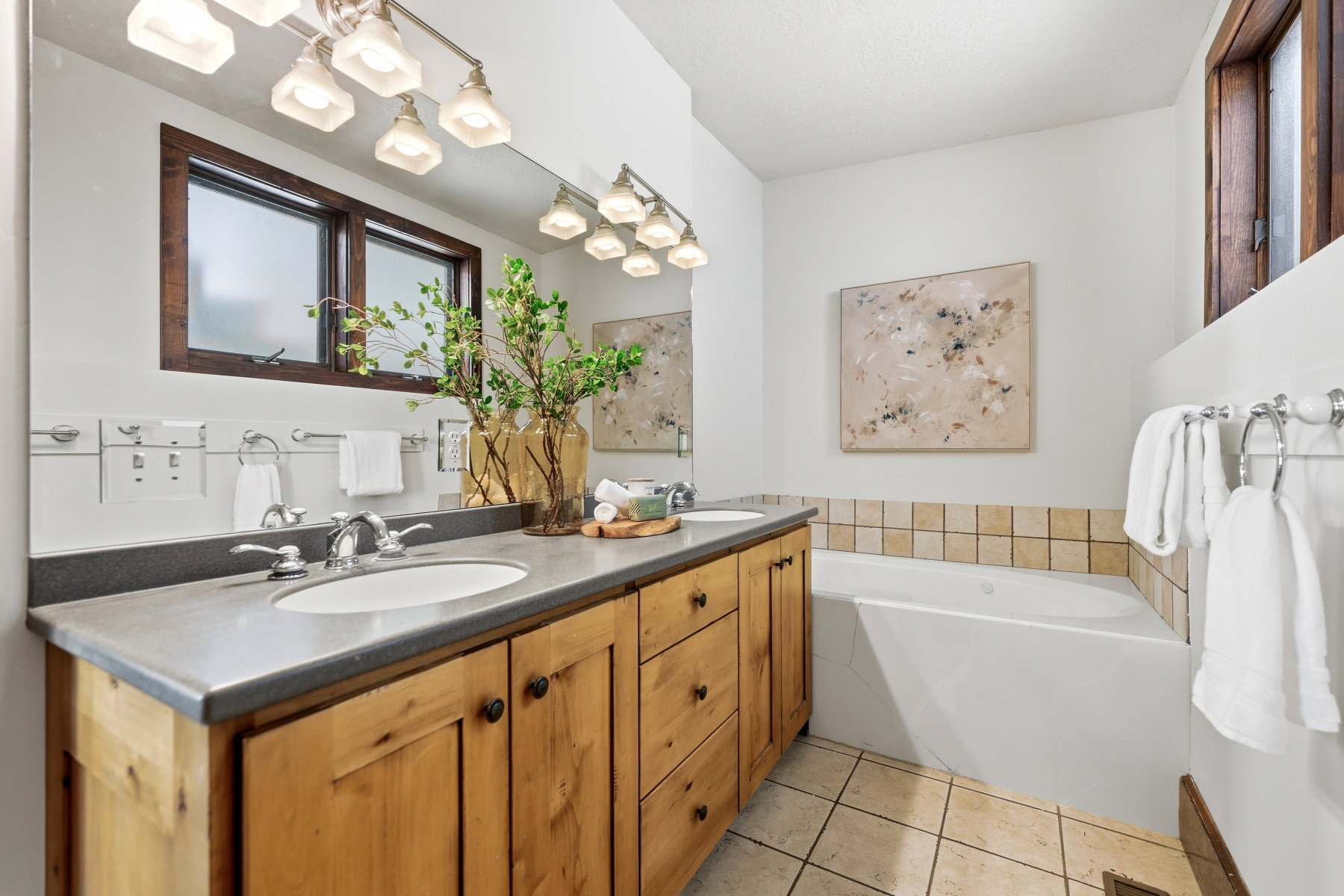 Dual vanity with light wood cabinetry and a dark countertop