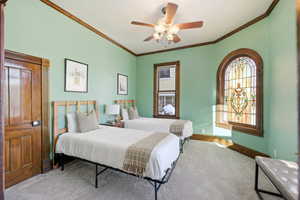 Carpeted bedroom featuring ceiling fan and crown molding