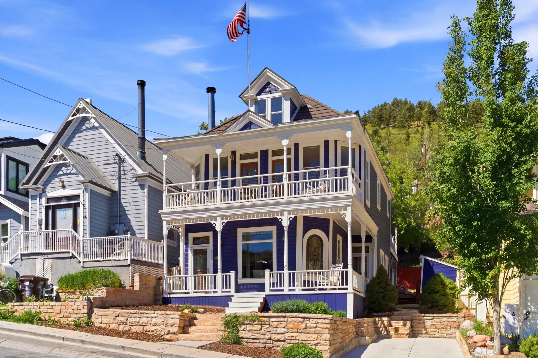 Victorian-style residence with a striking purple exterior, featuring white columned porches on both levels