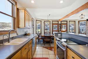 Kitchen featuring a chandelier, appliances with stainless steel finishes, pendant lighting, light tile patterned floors, and plenty of natural light