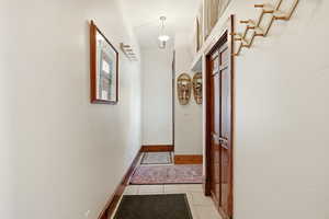 Hallway featuring light tile patterned floors and baseboards