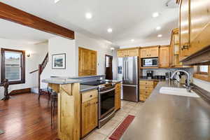 Kitchen with stainless steel appliances, a kitchen breakfast bar, an island with sink, recessed lighting, and brown cabinets