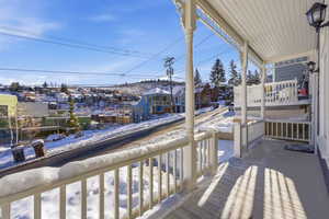 Snow covered back of property featuring covered porch and a residential view