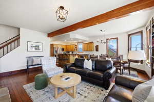 Living area featuring a chandelier, beam ceiling, recessed lighting, light wood finished floors, and stairs