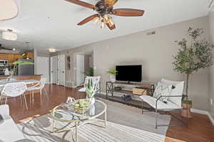 Living room featuring a ceiling fan and dark wood-style flooring