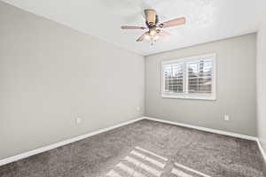 Carpeted secondary bedroom with plantation shutters and ceiling fan