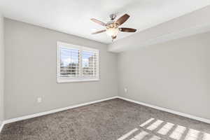 Carpeted secondary bedroom with plantation shutters and ceiling fan