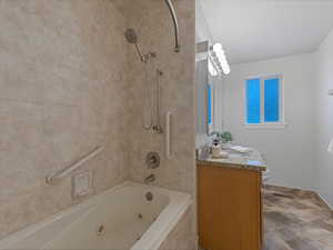 Bathroom featuring vanity and a combined bath / shower with jetted tub