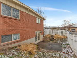 View of side of home featuring a fenced backyard, a patio, and brick siding