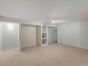 Unfurnished bedroom with light colored carpet and baseboards