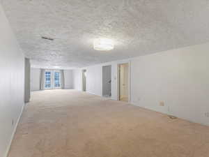 Carpeted spare room featuring a textured ceiling and french doors