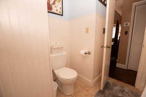 Half bath with toilet and light tile patterned floors