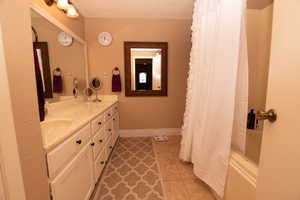 Bathroom featuring vanity, light tile patterned flooring, a textured ceiling, and shower / tub combo with curtain