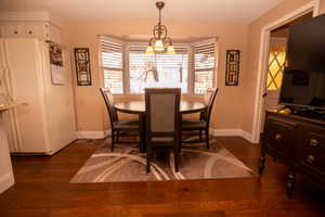 Dining space with dark wood-style flooring, a textured ceiling, and a chandelier