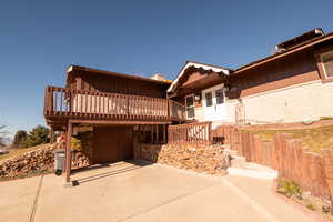 View of front of home with a deck, board and batten siding, stairs, and a patio area