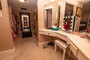 Ensuite bathroom featuring a walk in closet, vanity, and a textured ceiling