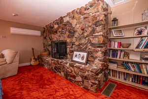 Living area with a textured ceiling, a fireplace, carpet flooring, and a wall mounted AC