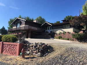 View of front of property with board and batten siding, a wooden deck, and brick siding