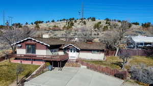View of front of home with a deck, a chimney, board and batten siding, and brick siding