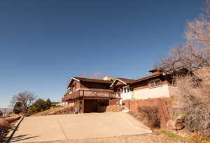 View of front of house featuring concrete driveway, a chimney, and a deck