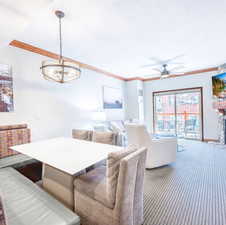 Carpeted dining room featuring crown molding, a textured ceiling, ceiling fan, and a fireplace
