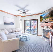 Carpeted living area featuring ornamental molding, a fireplace, a ceiling fan, and a textured ceiling