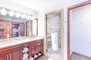Bathroom with double vanity, a stall shower, and light tile patterned flooring