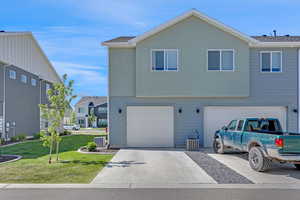 View of front of property with a front yard, driveway, an attached garage, and stucco siding
