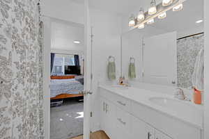 Ensuite bathroom featuring curtained shower, double vanity, recessed lighting, and light carpet