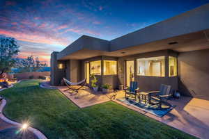 Back of property at dusk with stucco siding and a patio