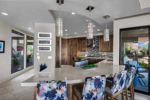 Kitchen featuring pendant lighting, backsplash, a breakfast bar area, a kitchen island, and recessed lighting