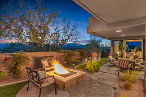 Patio terrace at dusk with a patio area, a fire pit, a fenced backyard, and a mountain view