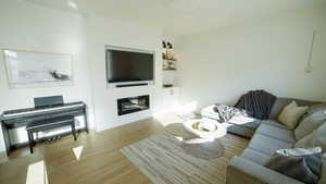 Living area with light wood-style flooring and a glass covered fireplace