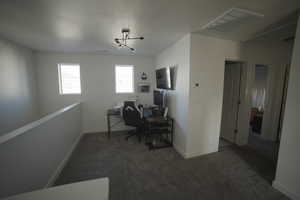 Office or loft area at the top of the stairs  featuring dark carpet and a textured ceiling