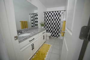 Full bathroom featuring vanity, light tile patterned floors, and shower / tub combo with curtain