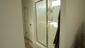 Ensuite bathroom with a large shower stall and light tile patterned flooring
